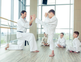 A man and boy in white uniforms practicing karate.